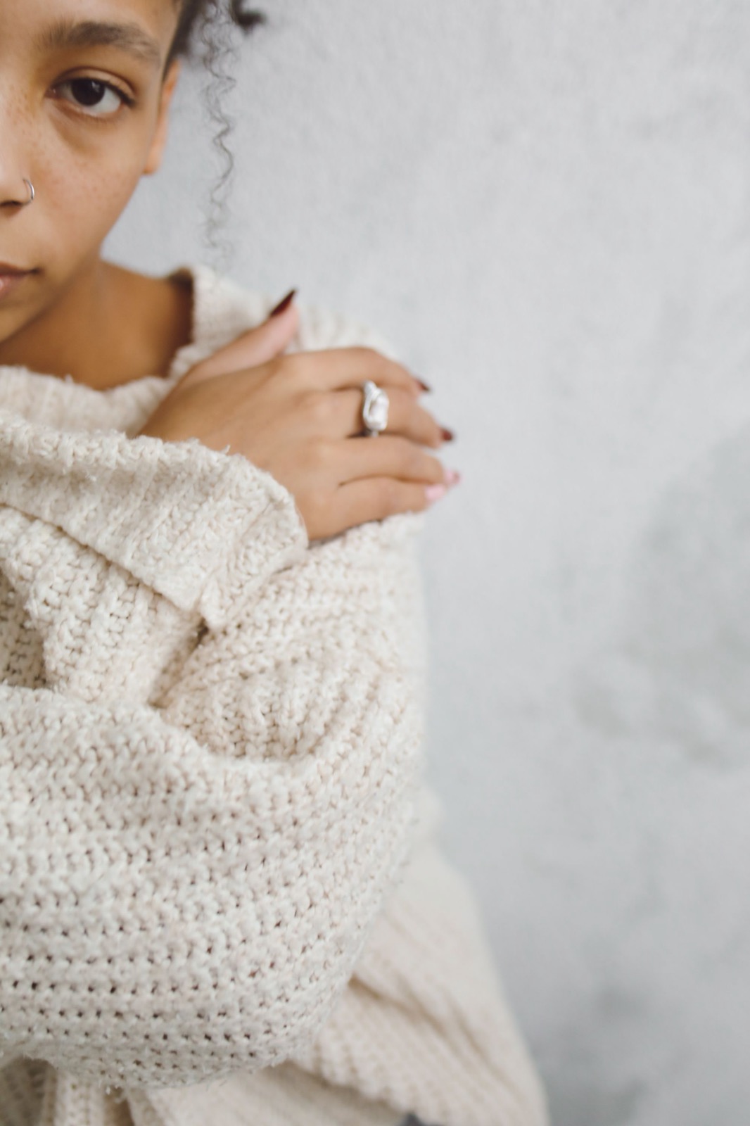 Close detail of a knitted sweater and a hand wearing a ring.